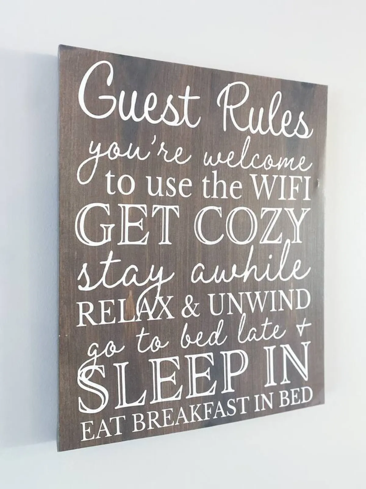A cozy interior space featuring a wooden sign with text, a comfortable bed, and a tray with breakfast items, suggesting a space where guests can relax, enjoy a quiet morning, or make use of the available WiFi. The scene feels welcoming and supports both social and individual moments.